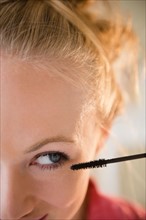 Close up of young woman using mascara