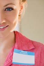 Portrait of smiling young woman with blank name tag