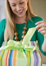 Smiling young woman opening birthday present