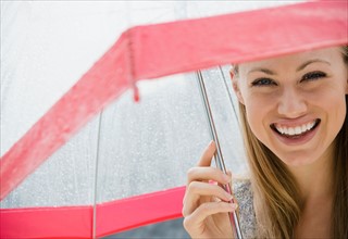 Portrait of smiling young woman with umbrella in rain