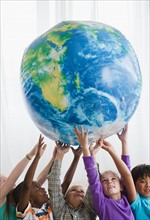 School children (8-9) lifting inflatable globe