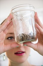 Young woman holding jar with coins