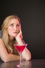 Young woman drinking martini and contemplating