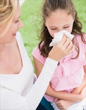 Mother helping daughter (8-9 years) to blow her nose