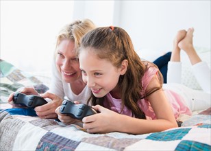 Mother and daughter (8-9 years) playing video games