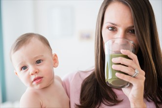 Mother with daughter (6-11 months) drinking vegetable smoothie