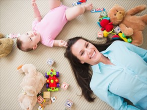 Mother with daughter (6-11 months) lying on floor