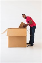 Studio shot of young man with large cardboard box