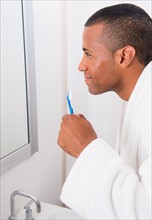 Young man with toothbrush in bathroom
