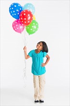 Studio shot of girl (6-7 years) holding colorful balloons