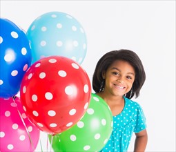 Studio shot of girl (6-7 years) with colorful balloons