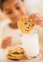Girl (6-7) having cookie and milk