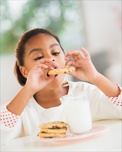 Girl (6-7) eating cookie