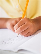 Girl (6-7) doing homework, close-up of hands