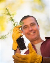 Portrait of man holding tree seedling