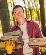 Portrait of Man holding armful of logs