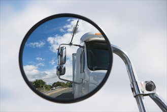 Reflection of semi-truck in side view mirror
