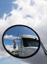 Reflection of semi-truck in side view mirror
