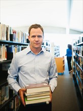 Man holding books in library