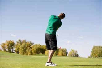 Rear view of man hitting ball on golf course
