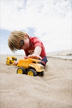 Boy (4-5) playing with truck in sand