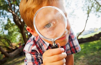 Little boy (6-7) looking through magnifying glass