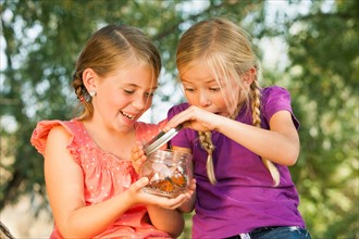 Two girls (4-5, 6-7) fascinated by butterfly in jar