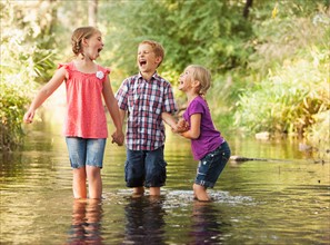 Three kids (4-5, 6-7) playing together in small stream