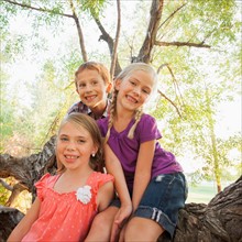 Three children (4-5, 6-7) smiling for portrait in huge tree
