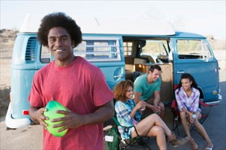 Man in foreground holding rugby ball with friends during their road trip