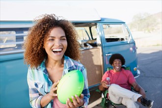 Woman in foreground holding rugby ball with friend during their road trip