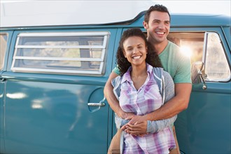 Young couple in front of mini van during road trip