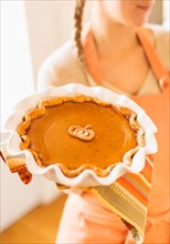 Woman holding pumpkin pie.