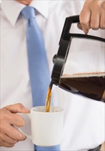 Businessman pouring coffee.