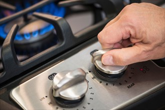 Close-up of hand adjusting stove burner.