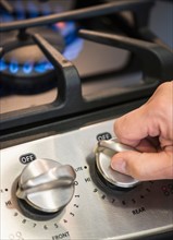 Close-up of hand adjusting stove burner.