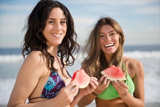 Two women eating watermelon at beach. Photo : Jamie Grill