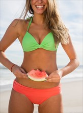 Woman eating watermelon at beach. Photo : Jamie Grill