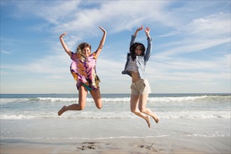 Two young women jumping on beach. Photo : Jamie Grill
