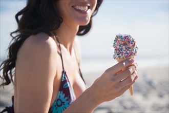 Woman eating icecream on beach. Photo: Jamie Grill