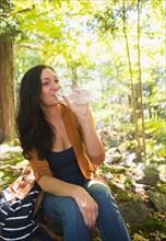 Woman drinking water in forest. Photo : Jamie Grill