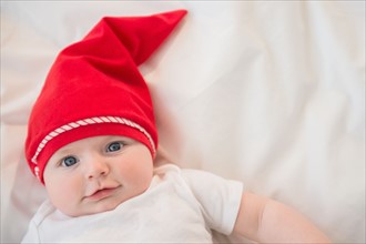 Portrait of baby boy (2-5 months) wearing red santa hat. Photo : Jamie Grill