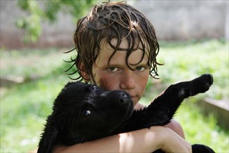 Portrait of wet Boy (10-11) with Labrador puppy . Photo: pauline st.denis