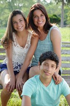 Outdoor portrait of smiling mother with daughter (12-13) and son (14-15). Photo: pauline st.denis