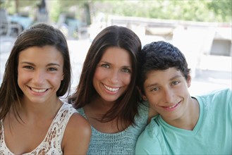 Outdoor portrait of smiling mother with daughter (12-13) and son (14-15). Photo : pauline st.denis