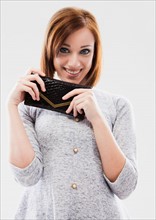 Portrait of young woman showing purse, studio shot. Photo : Mike Kemp