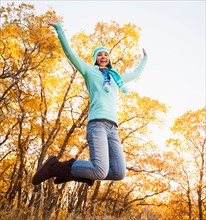 Happy young woman jumping in autumn forest. Photo : Mike Kemp