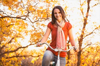 Happy young woman with bicycle in autumn in forest. Photo: Mike Kemp