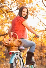 Happy young woman with bicycle in autumn in forest. Photo : Mike Kemp