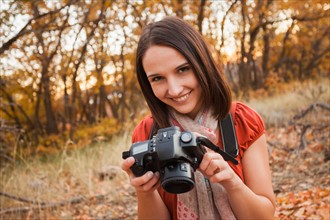 Portrait of smiling young woman lying on autumn leaves . Photo : Mike Kemp